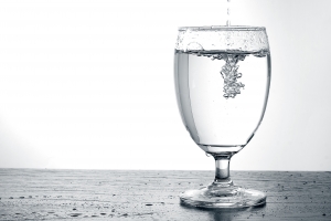 Pouring water into a glass on wooden table with copy space